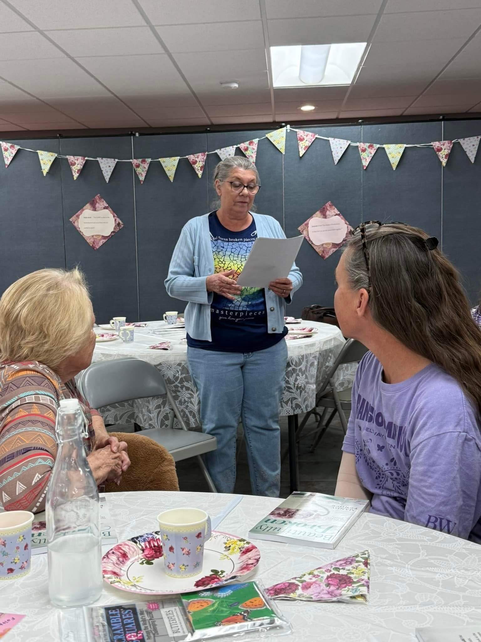 A woman stands reading to  two other women